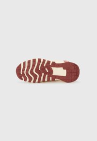 Piros és krém színű gumitalpú sneaker, mely texturált mintázattal rendelkezik a tapadás és a támogatás érdekében. Barázdákkal és sík sarok kialakítással rendelkezik.