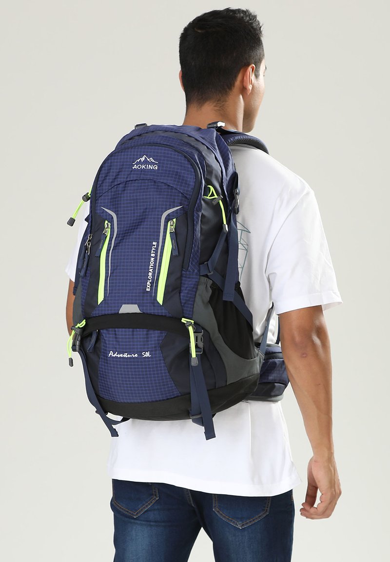 Zaino navy blue con più tasche e dettagli verdi, caratterizzato da un motivo a griglia, spallacci regolabili e schienale imbottito per il massimo comfort.