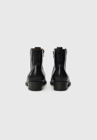 Black ankle boots featuring a textured, snake-skin pattern, sturdy heel, side zippers, and tan interior lining.