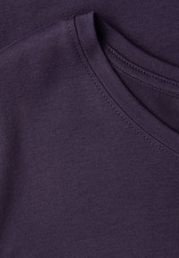 Fioletowa bawełniana tkanina o gładkiej fakturze, z zaokrąglonym dekoltem i płaskimi szwami, prezentująca prosty, minimalistyczny design.