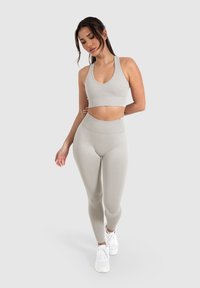Lichtgrijze sportoutfit bestaande uit een cropped sportbeha met een ronde halslijn en high-waisted legging. Gladde, rekbare stof met een geribde textuur.