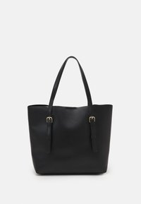 Musta kangaskassi, joka on valmistettu sileästä synteettisestä materiaalista, jossa on kaksi pitkää kahvaa ja kultasävytteiset solkiyksityiskohdat. Avoin yläpään muotoilu, minimalistinen muoto.