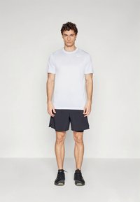 Abbigliamento sportivo maschile con maglietta bianca a maniche corte e pantaloncini neri, realizzati in tessuto leggero con scollo rotondo e logo Nike.