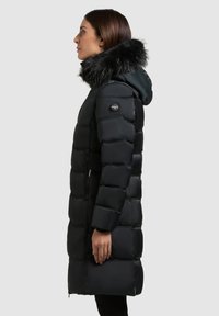 Svart vadderad kappa med en luvfodrad med päls, med quiltad design, dragkedjeförsedda framfickor och en logotypmärke på ärmen.