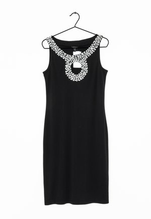 Robe noire sans manches avec un décolleté rond en forme de trou de serrure, décorée de grandes pierres blanches en strass, suspendue à un cintre noir.