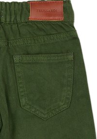Pantalon en denim vert avec une poche arrière cousue et une étiquette en cuir marron embossée du nom « TRUSSARDI » sur la ceinture.