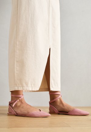 Roosa nahast korter sandaalid terava varbaga, õlavarrepael ja väike kuldne ripats, koos beeži põlvikute pikkusega seeliku ja.