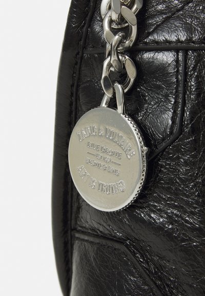 Black leather handbag featuring a textured finish, silver chain hardware, and a round metal tag with embossed lettering.