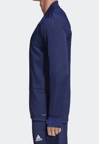 Mörkblå långärmad träningströja med rundad halsringning, ribbade detaljer på ärmarna och två framfickor. Tillverkad av ett slätt och lätt tyg.