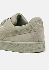 Zielone zamszowe sneakersy z teksturowaną gumową podeszwą, z przeszytymi akcentami i małym logo na obcasie. Okrągły czubek, niski profil.