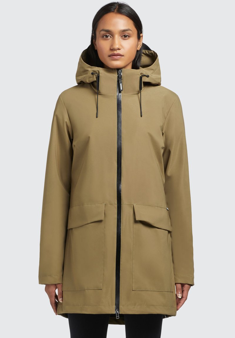Khaki nepremokavá parka s kapucňou, čierny zips, dve predné vrecká a rovný strih. Hladká tkanina s matným povrchom.