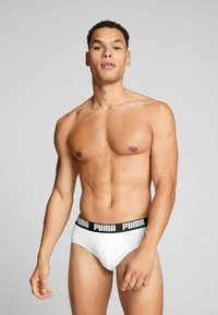Weiße Boxershorts mit einem schwarzen elastischen Bund mit "PUMA"-Logo. Glatte Textur, figurbetonte Form und minimalistisches Design.