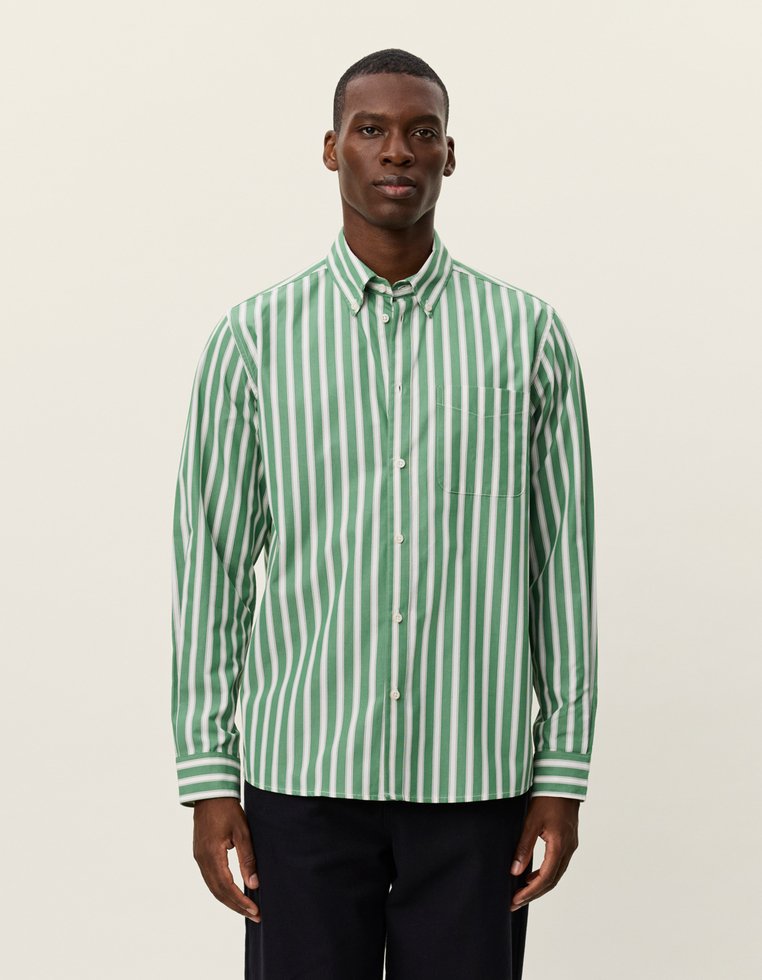 Zaļi un balti svītrota krekls, ar pogu aizdari, garām piedurknēm, viena krūšu kabata, gluda tekstūra un klasiskā apkakle.