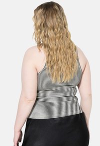Sort og hvid stribet tanktop med tynde stropper, lavet af et strækbart stof, der viser en tætsiddende silhuet og glat tekstur.