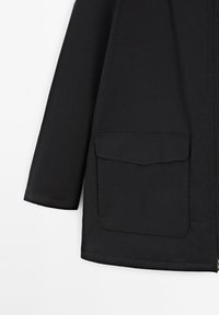 Schwarze Jacke mit einem Reißverschluss, langen Ärmeln und einer großen Fronttasche. Der Stoff wirkt glatt mit mattem Finish. Lässiges Design.