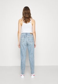 Vaaleansiniset, korkean vyötärön farkut, joissa on kapenevat lahkeet. Niissä on ruskea nahkapatchi takana ja kaksi takataskua.