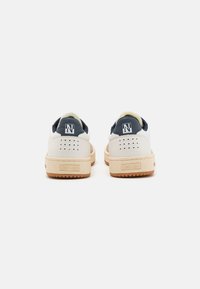 Sneaker bianche in pelle con dettagli in blu navy, una suola testurizzata e perforazioni sul tallone. Presentano un logo sul retro.