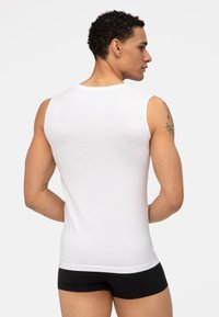 Witte mouwloze tanktop gemaakt van zachte stof, met een ronde hals en een effen ontwerp. De achterkant toont een gladde textuur en een strakke pasvorm.