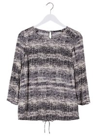 Blouse à motif texturé noir et blanc avec manches trois-quarts, encolure ronde, ouverture au dos avec bouton et cordon de serrage à l'ourlet, suspendue à un cintre blanc.