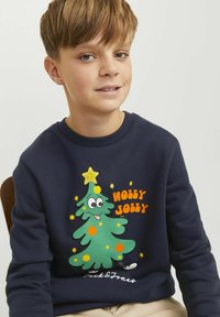 Tengerészeti pulóver színes mesefigurás karácsonyfával. Narancssárga felirattal: "HOLLY JOLLY", csillag díszítéssel, és zöld pöttyökkel a fán.