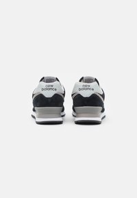 Czarne i szare sneakersy New Balance z cholewką z zamszu i siateczki, białymi akcentami oraz amortyzowaną podeszwą środkową. Tylny widok ukazuje szczegóły logo.