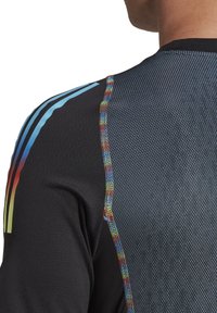 Maglietta sportiva nera a maniche corte con strisce blu e dettagli di cucitura multicolore sulla spalla, caratterizzata da un motivo in mesh testurizzato.