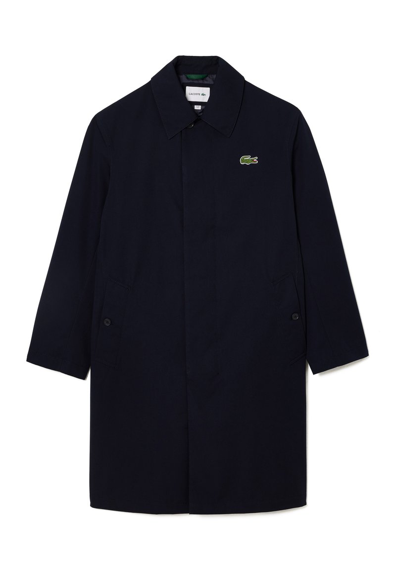 Trench azul marino con cuello puntiagudo, bolsillos laterales y un logo bordado en verde. Fabricado en una tela suave con un corte holgado.