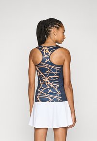 Marin blå idrettstopp med oransje abstrakte mønstre, tettsittende design, racerback-utskjæring, kombinert med en hvit perforert skjørt.