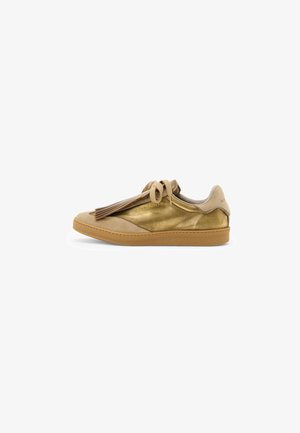 Sneaker bassa in pelle dorata e suede beige con suola in gomma, lacci piatti e dettaglio frangiato decorativo su uno sfondo bianco.