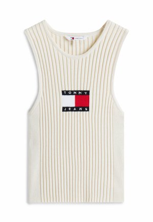 Żakardowy, bezrękawnik w jasnym kremowym kolorze z naszywką logo w granatowym, czerwonym i białym kolorze. Miękka tekstura i luźny krój.