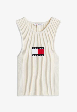 Żakardowy, bezrękawnik w jasnym kremowym kolorze z naszywką logo w granatowym, czerwonym i białym kolorze. Miękka tekstura i luźny krój.