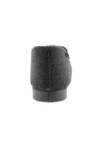 Pantufla de lana gris oscuro con un respaldo redondeado, suela de goma negra y detalles de costura mínimos. Textura suave, diseño simple.