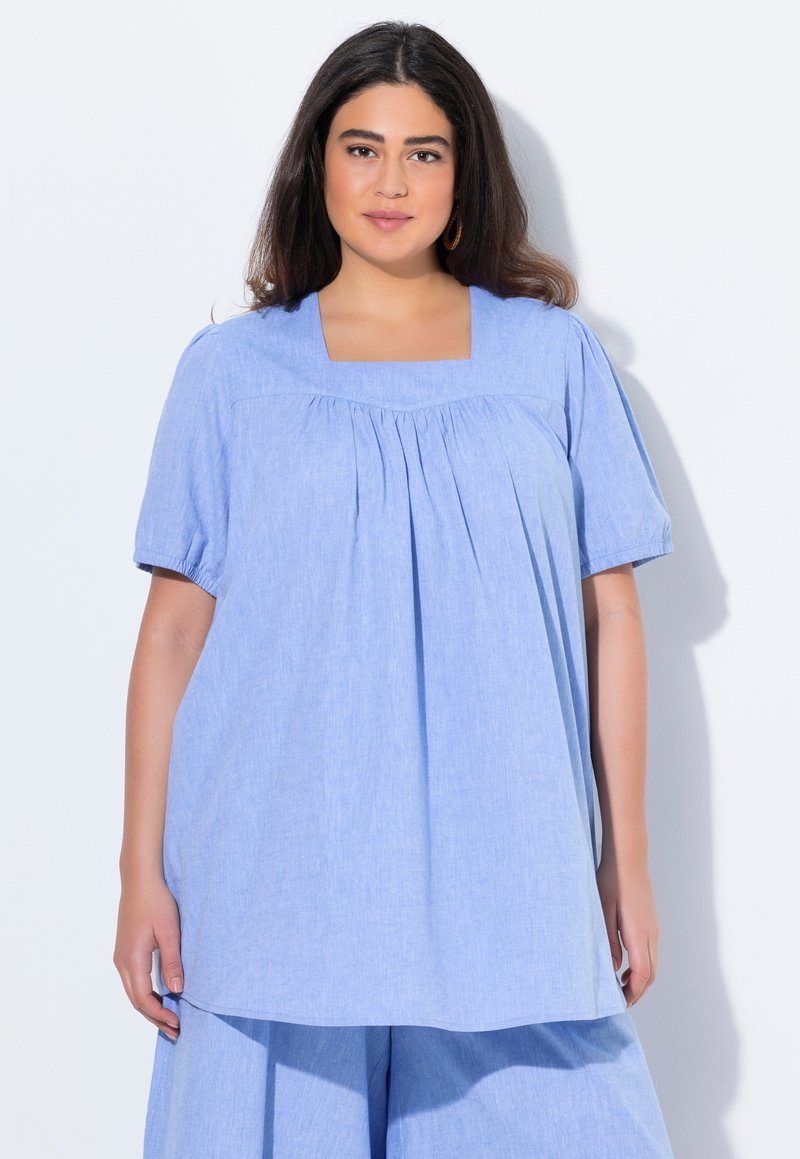 Blusa azzurro chiaro a maniche corte con scollatura quadrata e dettagli arricciati, realizzata in un tessuto texture, abbinata a pantaloni larghi coordinati.