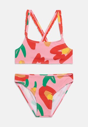 To-delt rosa badedrakt med røde, grønne og gule abstrakte blomsterprint; overdelen har kryssede, rynkede skulderstropper.