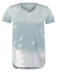 Camiseta de cuello en V de color azul claro con un diseño de degradado y patrones de salpicaduras blancas, y un dobladillo trasero más largo. Fabricada con tela suave.