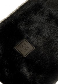 Prodotto in finta pelliccia nera con una texture liscia e morbida. Presenta una toppa quadrata in pelle con un logo impresso nell'angolo.