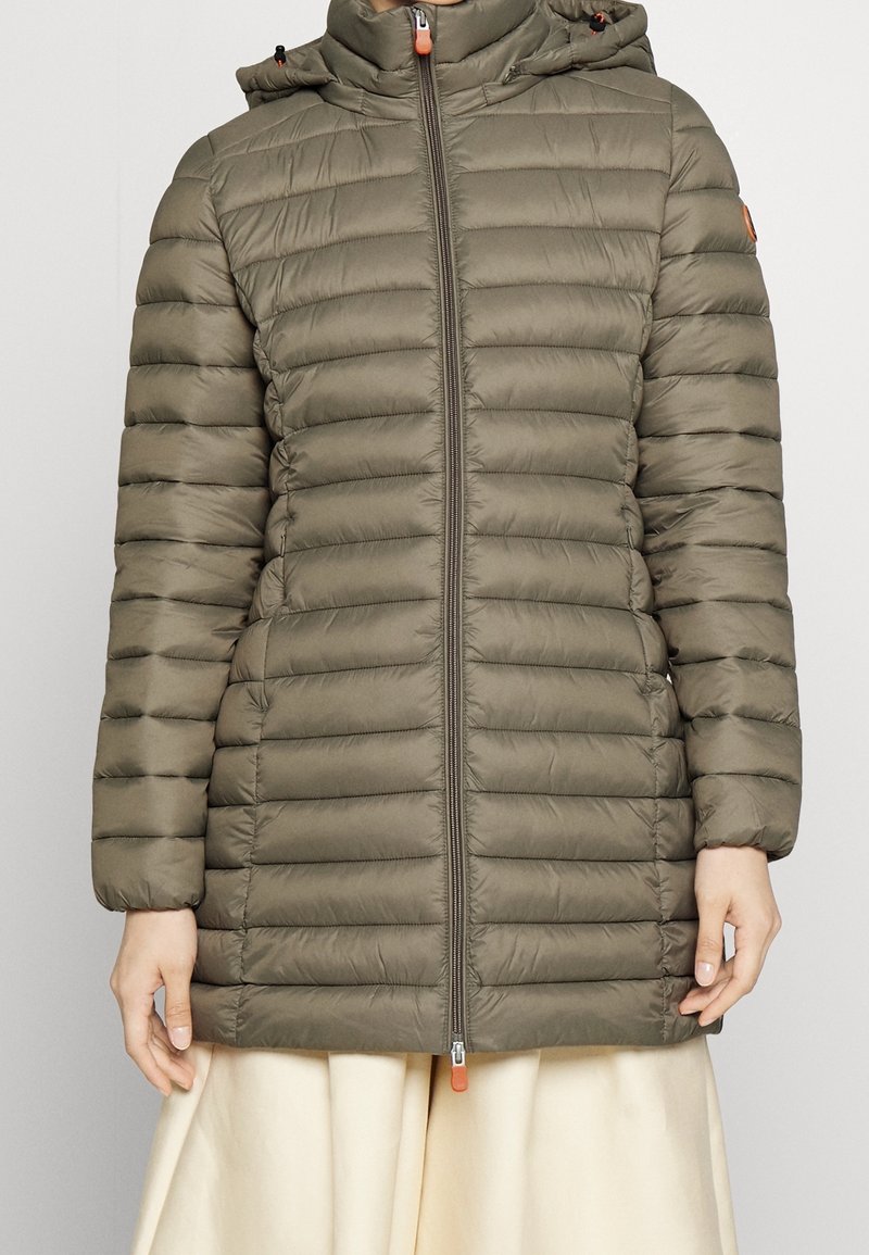 Parka matelassée en vert olive, avec des sections matelassées horizontales, une capuche, une fermeture éclair à l'avant avec un tirant orange, et des poignets élastiques.