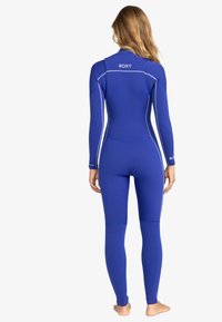 Blue wetsuit with long sleeves, featuring white stitching accents and logo on the back, made from flexible neoprene material.