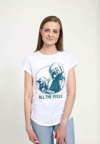 Hvid t-shirt med korte ærmer, der har en blå grafik af en karakter, der holder en anden karakter, med teksten "ALL THE FEELS" nedenfor.