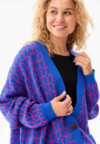 Blauwe cardigan met een honingraatpatroon in het roze. Zachte breimateriaal, relaxte pasvorm, met een knoopsluiting en geribbelde manchetten.