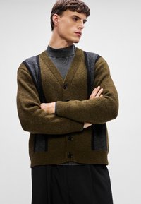 Ελιάς πράσινο cardigan με υφασμάτινη πλέξη, που διαθέτει ναυτικές και γκρι λεπτομέρειες σε ρίγες, πέντε κουμπιά και σχέδιο σε σχήμα V.