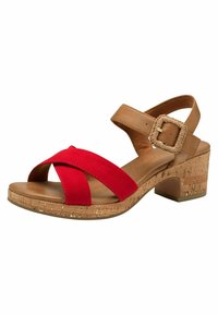 Sandalia de ante rojo con un diseño entrecruzado, correas de cuero marrón claro y un tacón de bloque con textura de corcho. Presenta un detalle de hebilla trenzada.
