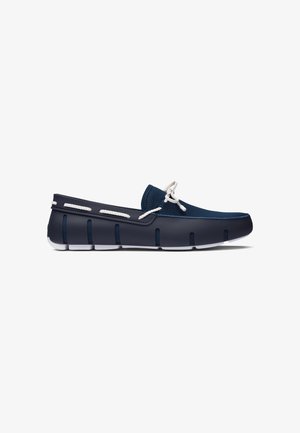 Marineblauwe slip-on bootschoen met witte touwveters en witte gesegmenteerde rubberen zool, ontworpen voor casual gebruik.