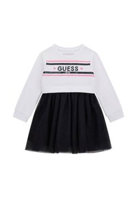Långärmad klänning med en vit överdel med svarta och rosa ränder och texten "GUESS", tillsammans med en svart volangkjol.