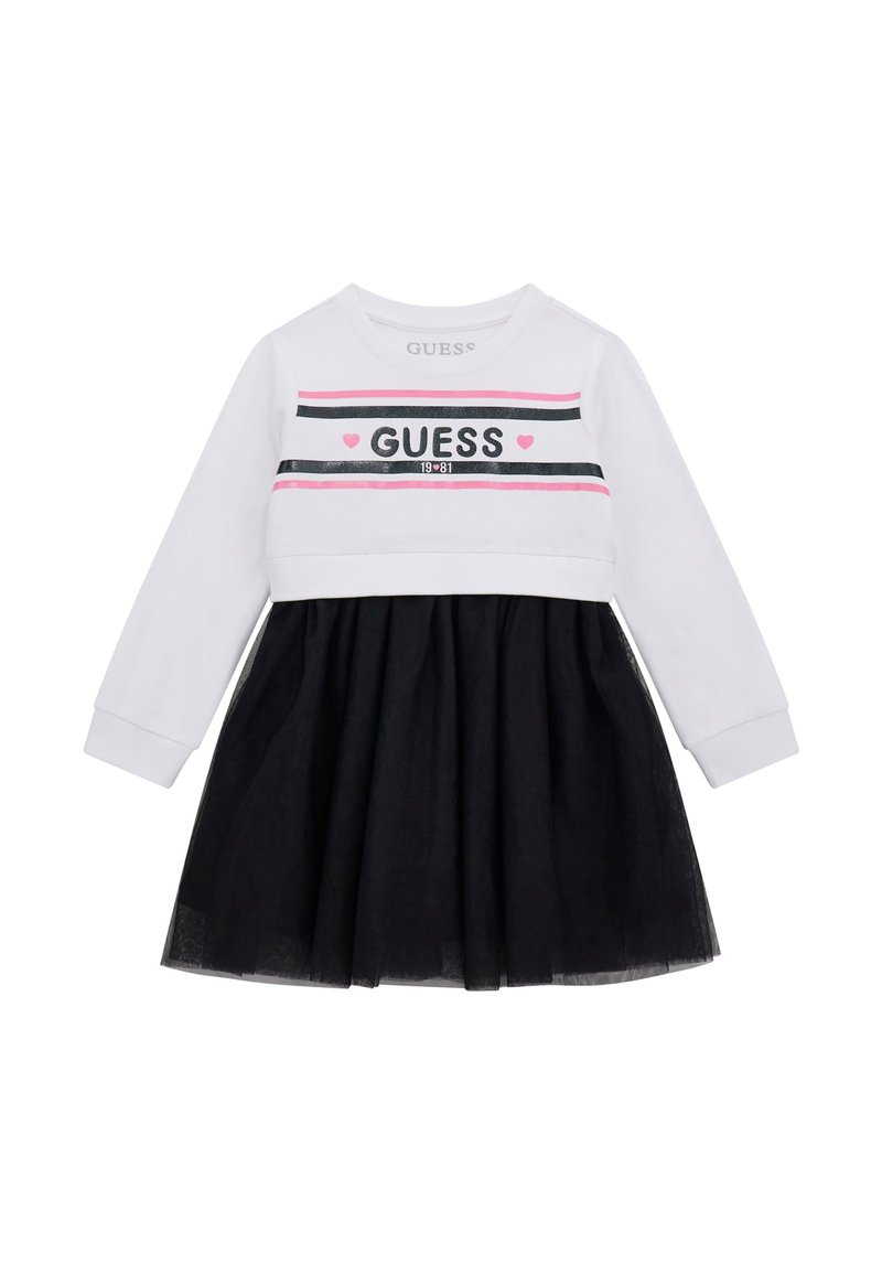 Långärmad klänning med en vit överdel med svarta och rosa ränder och texten "GUESS", tillsammans med en svart volangkjol.