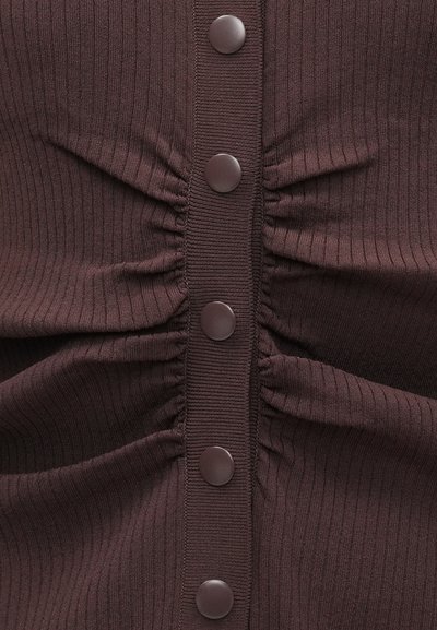 Σκούρο καφέ πλεκτό τοπ με μαζεμένες πλευρές και πέντε μεγάλα, στρογγυλά καφέ κουμπιά κατά μήκος του κέντρου. Ομαλή υφή με κάθετες γραμμές.