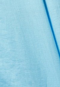 Tissu bleu clair avec une texture de tissage visible et un pli doux créant une ombre sur le côté droit.