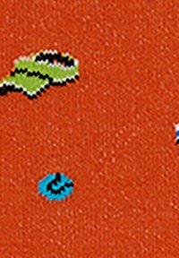 Orange fabric featuring a textured surface with scattered patterns of green, blue, and black shapes.