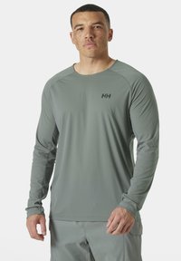 Langdraagshirt in lichtgrijs met subtiele strepen. Heeft een ronde hals, raglanmouwen en een zwart logo op de borst.