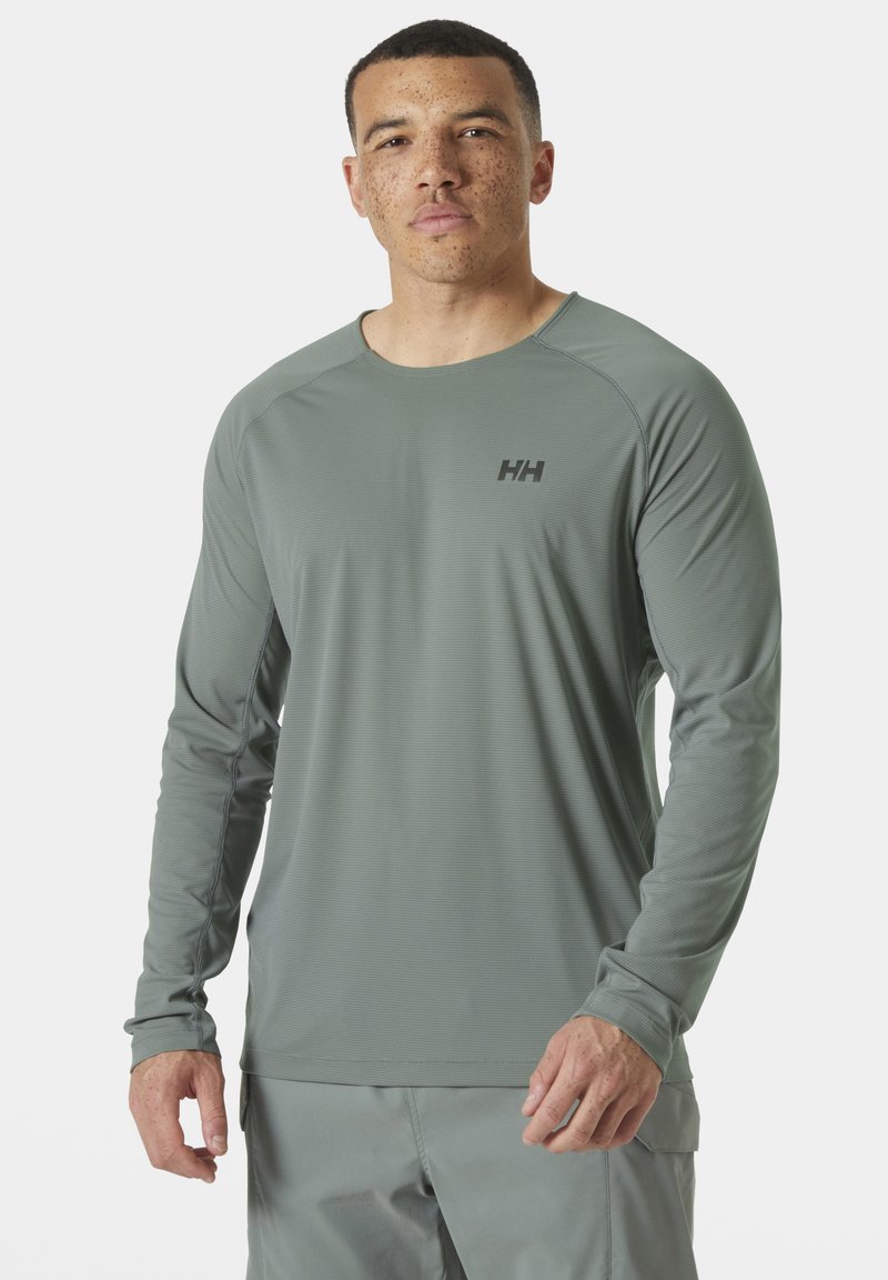 Dlouhý rukáv sportovní tričko v světle šedé barvě s jemnými pruhy. Má crew neck, raglánové rukávy a černé logo na hrudi.